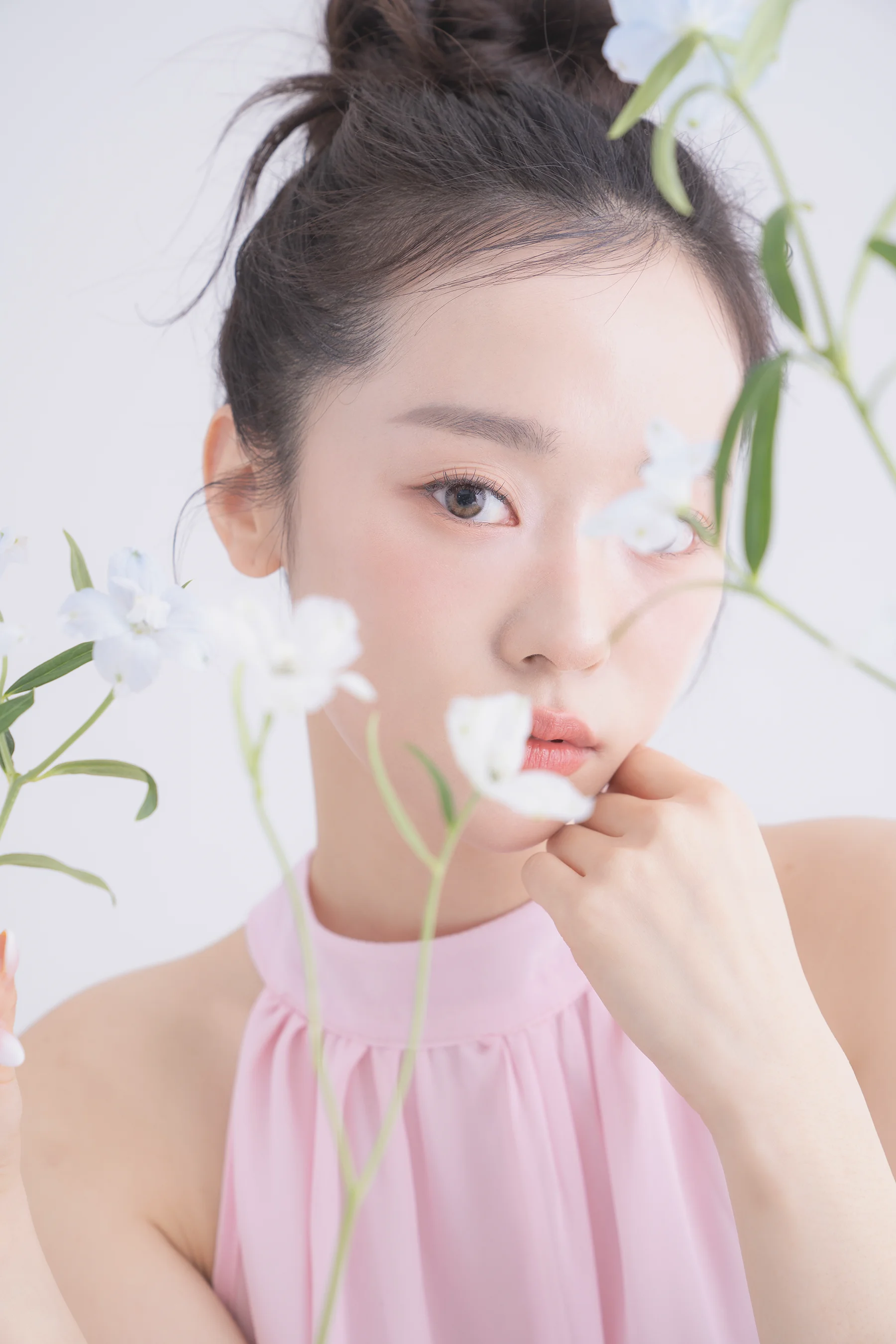 花瓶の花越しに片目をのぞかせる女性。穏やかで控えめな表情